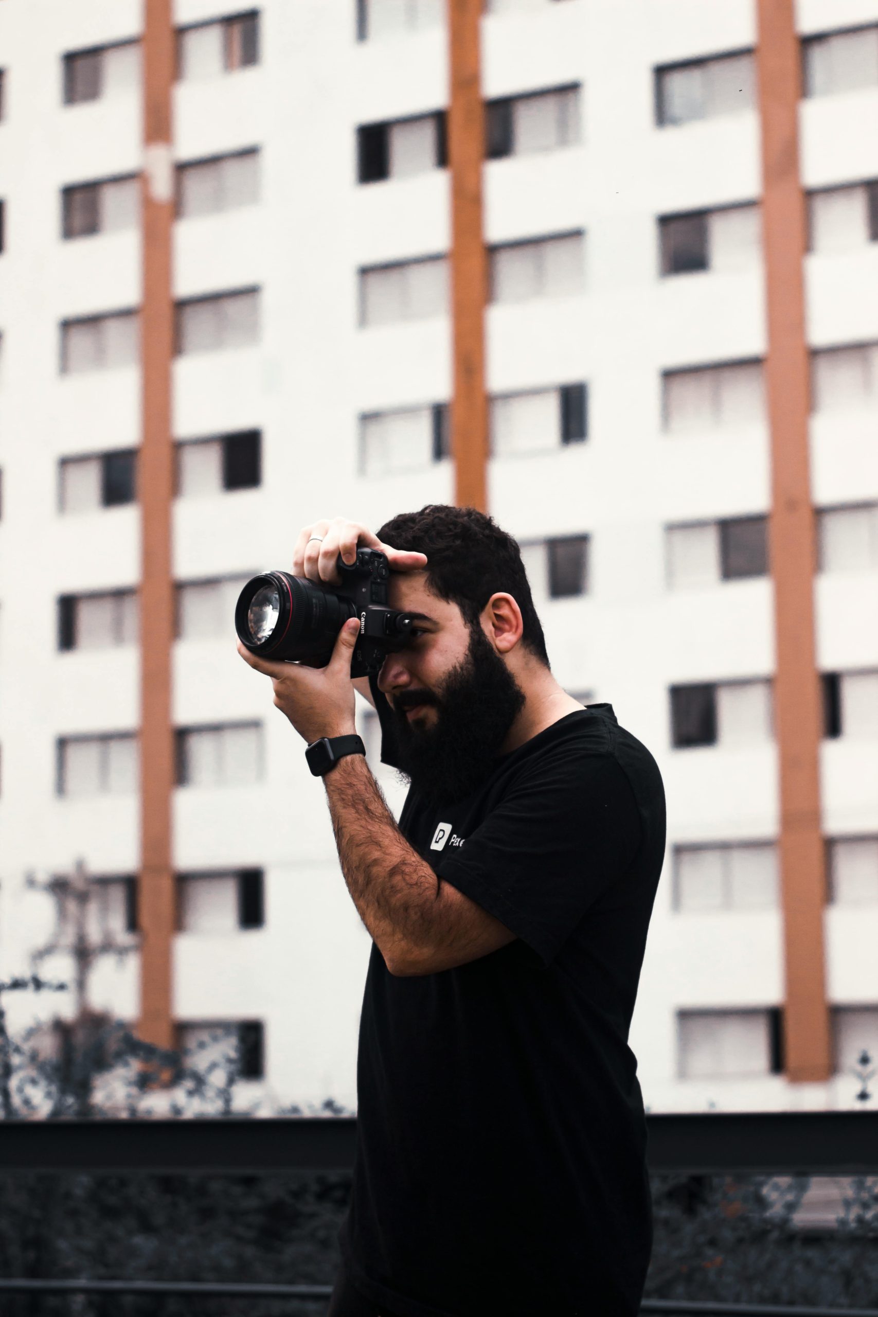 Photographer capturing urban scenes outdoors with focus and style.